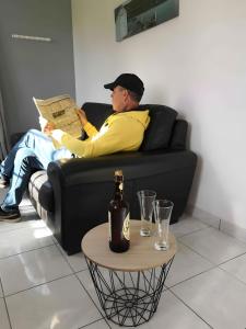 a man sitting on a couch reading a newspaper at Gîte de Rosemont in Saint-Pol-sur-Ternoise +2 photos