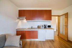 a kitchen with wooden cabinets and a couch in a room at Fichtenhof Wohnung Edelweiss in Tarces +17 photos