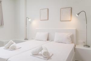 a white bedroom with two beds and a bathtub at A Tinian Room 2 in Tinos +15 photos