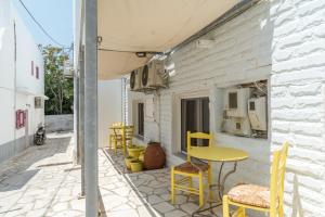 a patio with yellow chairs and a yellow table at A Tinian Room 2 in Tinos