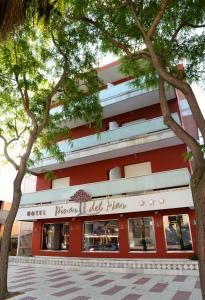 um edifício vermelho com árvores em frente em Hotel Spa Pinar del Mar em Platja d'Aro