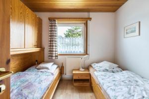 two beds in a small room with a window at Ferienhaus Herich in Nieblum