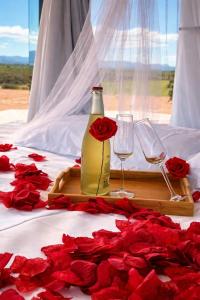 a bottle of wine and two glasses on a bed with roses at La Casa del Desierto in Gorafe