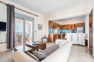 a living room with a white couch and a kitchen at Blue Pearl Apolakkia in Apolakkiá