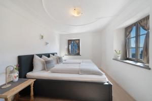 a bedroom with a bed with white walls and windows at Apartment Am Grübl in Lana