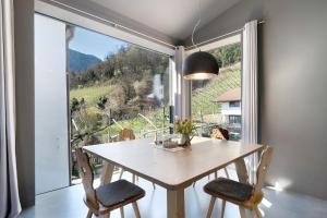 a dining room with a table and chairs and a large window at Apartment Am Grübl in Lana