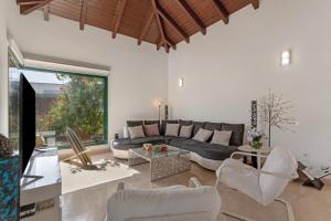a living room with a black couch and white chairs at El refugio in La Oliva