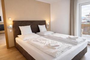 a bedroom with two beds with white sheets and a window at Premium App Hofer Barbara in Villabassa
