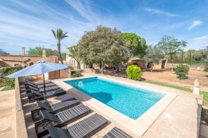 an outdoor swimming pool with chairs and an umbrella at Finca Can Menut in Felanitx