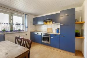 a kitchen with blue cabinets and a wooden table at Ferienwohnung Lichte in Medebach