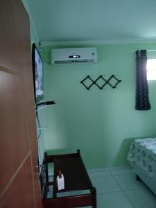 a room with green walls and a tv and a table at Flats Xingó in Piranhas