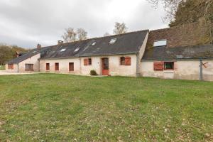a white house with red doors and a grass field at La Petite Trigalière in Ambillou