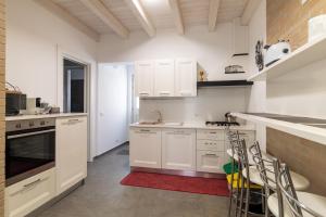 a kitchen with white cabinets and a red rug at Chibao House con piscina privata in Ragusa