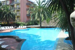 a large swimming pool with palm trees and a building at Appartamento Monolocale Moneglia 35 in Moneglia