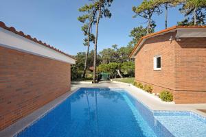 a swimming pool next to a brick building at Moradia Pinheiro Manso in Apúlia
