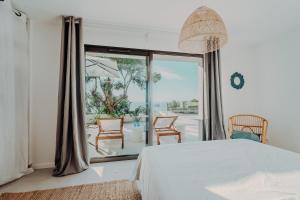 a bedroom with a bed and a large window at La Thébaïde in Cargèse