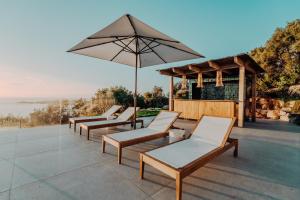 a row of chairs and an umbrella on a patio at La Thébaïde in Cargèse
