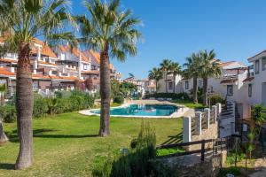 a resort with a swimming pool and palm trees at Atico Duplex con terraza in Manilva