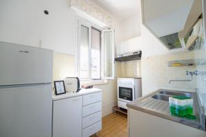 a white kitchen with a sink and a refrigerator at La casa di Greta in Marcelli
