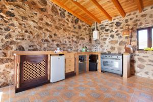 a kitchen with a stone wall and a white refrigerator at Casa los Javieles in Puerto del Rosario +13 photos