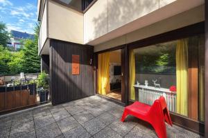 a red chair sitting on a patio in front of a house at Waldquartier in Schönwald