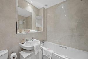 a bathroom with a sink and a mirror and a tub at Lees Apartment in Coatbridge