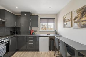 a kitchen with black cabinets and a counter top at Lees Apartment in Coatbridge