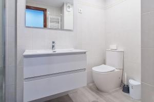 a white bathroom with a sink and a toilet at Vivienda Turística Osiris in San Andrés del Rabanedo