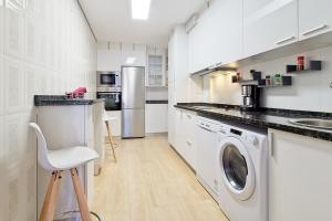 a white kitchen with a washer and dryer in it at Vivienda Turística Osiris in San Andrés del Rabanedo