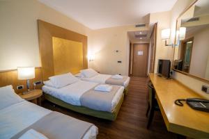 a hotel room with two beds and a television at Hotel Tiffany Milano in Trezzano sul Naviglio