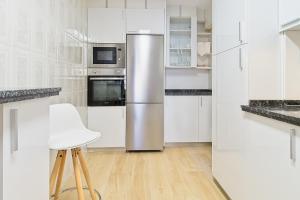 a kitchen with white cabinets and a stainless steel refrigerator at Vivienda Turística Osiris in San Andrés del Rabanedo +15 photos
