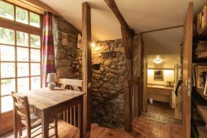 a dining room with a table and a stone wall at Les Grisiéres in Montpezat-sous-Bauzon