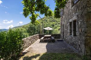 a picnic table with an umbrella next to a stone building at Les Grisiéres in Montpezat-sous-Bauzon