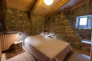 a bedroom with a bed in a stone wall at Les Grisiéres in Montpezat-sous-Bauzon