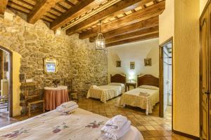 a room with two beds and a stone wall at La Torre de Dalt in Santa María de Camós +37 photos