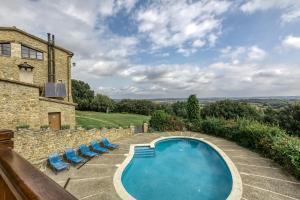 a swimming pool in front of a building with blue lounge chairs at La Torre de Dalt in Santa María de Camós