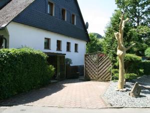 a house with a gate and a tree in a driveway at Fewo am See in Olsberg