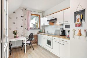 a kitchen with white cabinets and a table with chairs at Fewo am See in Olsberg