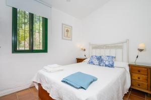 a bedroom with a white bed with blue pillows at Finca Encina - piscina compartida in Alájar