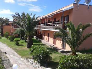 a building with palm trees in front of it at Monolocale Sergi- Piscina In Comune in Stintino