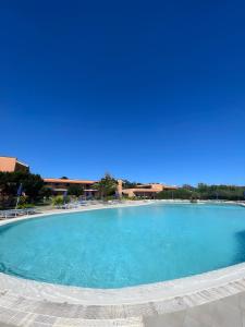 a large swimming pool with blue water at Monolocale Sergi- Piscina In Comune in Stintino
