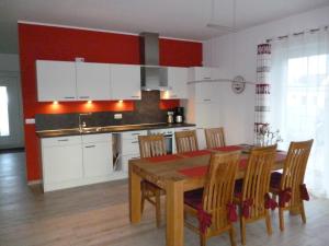 a kitchen with a wooden table and a kitchen with white cabinets at Ankerhaus mit Sauna und Kamin in Karlshagen +13 photos