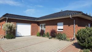 a red brick house with two white garage doors at Ankerhaus mit Sauna und Kamin in Karlshagen