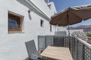 a wooden table with an umbrella on a balcony at El Blanquizal B in San Nicolás
