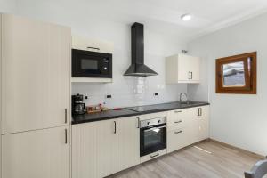 a kitchen with white cabinets and a black counter top at El Blanquizal B in San Nicolás