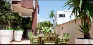 a patio with green chairs and tables and plants at Bnb Sottosopra intero 3 stanze 8pax in Gallipoli