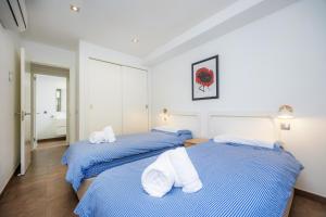 two beds in a bedroom with blue and white sheets at Bergantin 7 in Port de Pollensa +29 photos