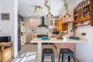 a kitchen with a white counter and two stools at Casa El Naranjo Azul Granada in Lecrin