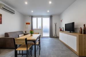 a living room with a dining room table and a television at Emmeci House in Alghero
