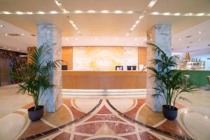 a lobby with two potted plants in front of a counter at Hotel Tiffany Milano in Trezzano sul Naviglio +33 photos